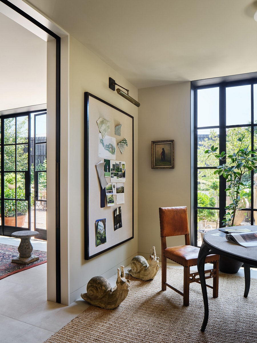 Corner of Jackie Harrison's office with project moodboard on the wall and two large stone snail statues on floor